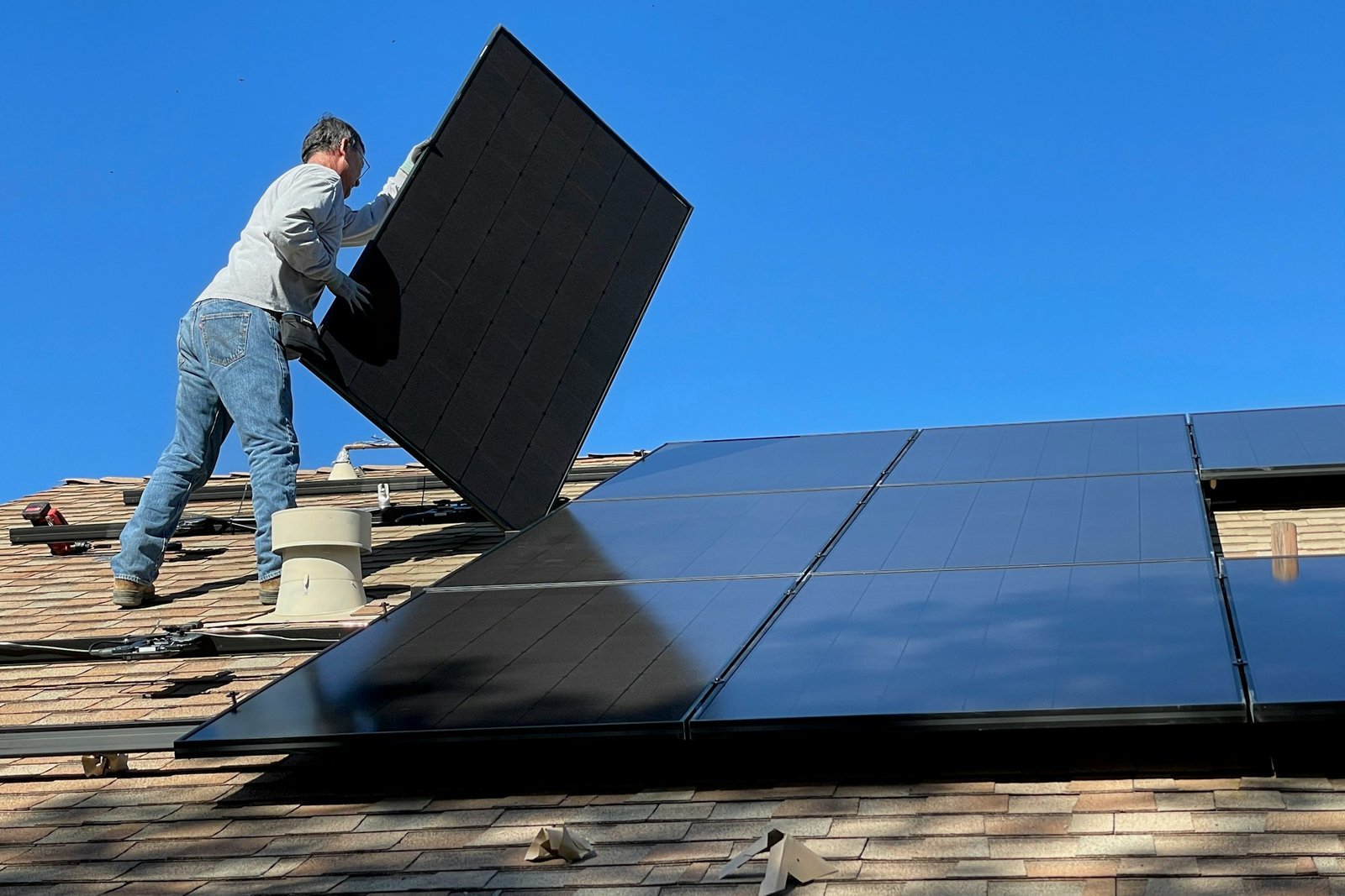 Instalador posicionando um módulo fotovoltaico no telhado